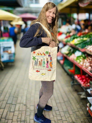 Woman holding a tote bag with colorful designs in an outdoor market setting