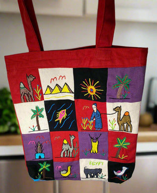 Red tote bag with colorful  embroidered designs on a blurred background