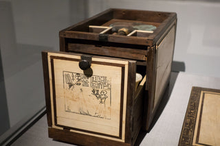 The photo depicts the Cosmetic Box of Kemeni which is a cedar cosmetic box, with ebony and ivory veneer and silver mounting, of the Cupbearer Kemeni, Middle Kingdom of Egypt, 12th Dynasty, reign of Amenemhat IV, c. 1814-1805 BCE.
