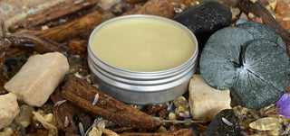 Balm in a metal container surrounded by natural elements like stones and plants