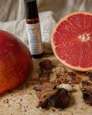 Grapefruit, mango, and a bottle of essential oil on a textured surface