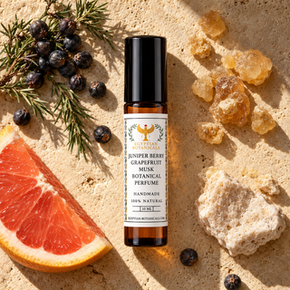 A 10 ml roll-on bottle of Egyptian Botanicals Juniper Berry Grapefruit Musk Botanical Perfume, featuring an amber glass bottle, a black cap, and a white label with gold and black text.