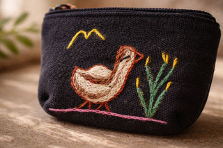 Black pouch with embroidered chicken design on a wooden surface