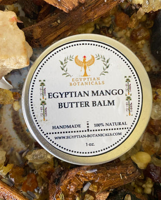 Egyptian Mango Butter Balm tin surrounded by natural elements on a textured surface