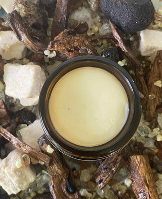 Jar of  balm on a natural background with herbs and stones