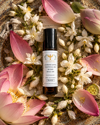 A natural botanical perfume roll on
Jasmine Lotus Natural Botanical Perfume by Egyptian Botanicals styled in a flat-lay with pink lotus petals and small white flowers on a textured stone background.