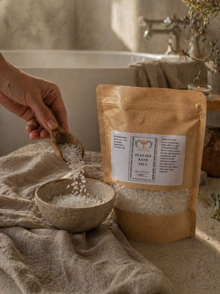 Person pouring Dead Sea bath salt into a bowl with a package of the product in the background.