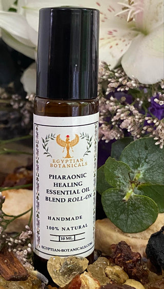 Roll-on bottle of Pharaonic Healing Essential Oil Blend by Egyptian Botanicals on a natural background with herbs and flowers.