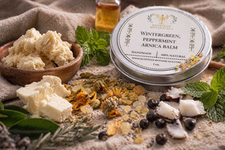 Balm tin labeled 'Wintergreen, Peppermint, Arnica Balm' surrounded by natural ingredients on a textured surface.